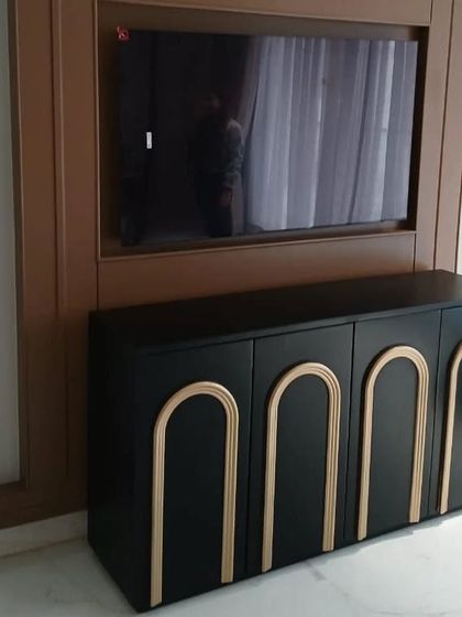 This striking black TV console features arched, gold-tone details on its four doors. The bold contrast and art-deco-inspired design make it a glamorous and sophisticated addition to any entertainment area.