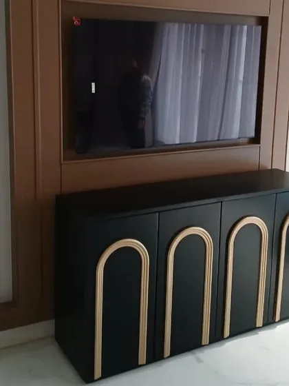 This striking black TV console features arched, gold-tone details on its four doors. The bold contrast and art-deco-inspired design make it a glamorous and sophisticated addition to any entertainment area.