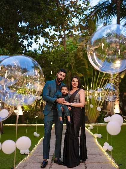 A stylish family portrait taken during a milestone birthday celebration. The large, clear balloons and evening lights add a touch of modern elegance to the photo.