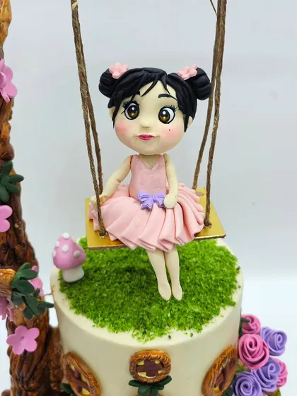 A close-up of the delicate, hand-sculpted fairy girl figurine on her swing.