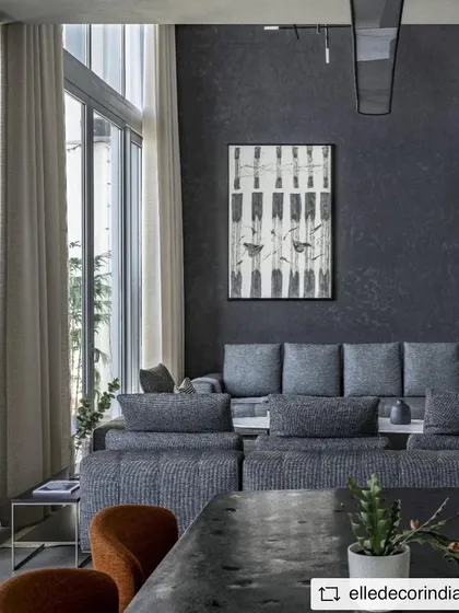 The main living area features a striking black textured wall that provides a dramatic backdrop for the contemporary art and minimalist furniture. The open-plan layout connects the living and dining areas, flowing out to an open-to-sky balcony.