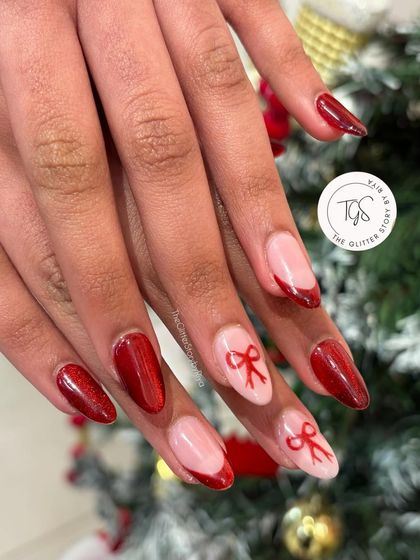 A classic Christmas nail set. This design combines deep red nails, a red French tip, and accent nails with adorable, hand-painted red bows.