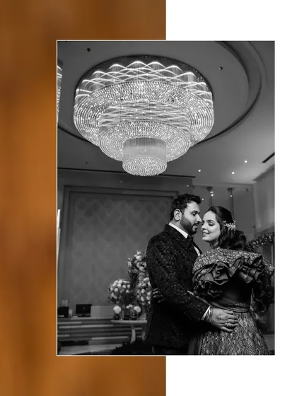 A beautiful black and white portrait of the couple under a grand chandelier. The monochrome tones add a timeless, classic feel to this romantic reception moment.