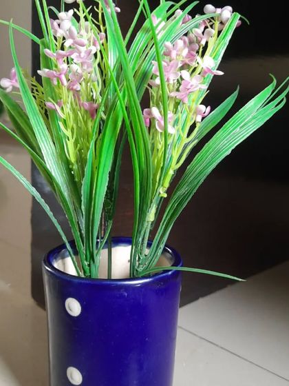 A simple blue ceramic pot with white polka dots, holding a bunch of artificial lavender. It's a cheerful and charming piece for adding a small touch of colour.