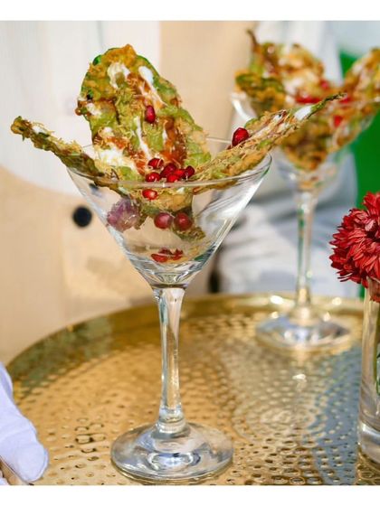 Our signature Palak Patta Chaat, with crispy spinach leaves, yogurt, and pomegranate seeds, served in a martini glass. This is a perfect example of our modern and stylish approach to classic Indian flavours.