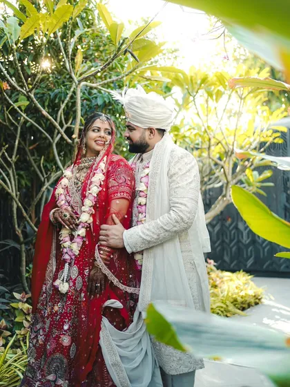 A beautiful portrait of a couple in a garden setting, framed by lush greenery. Their happy expressions show the joy of their wedding day.