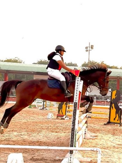 A young rider from our team clears a jump during a national qualifier event. We are incredibly proud of her outstanding performance.