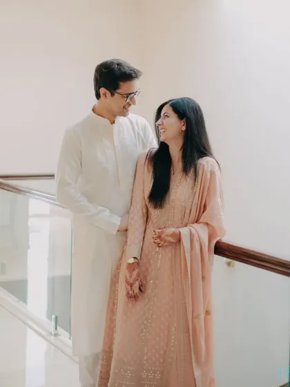 A sweet, shared glance. The couple's minimalist attire and the clean, bright background keep the focus entirely on their interaction and the happiness they share.