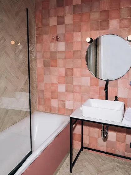 After: The finished bathroom, now a stylish and modern space with pink mosaic tiles, a sleek bathtub, and contemporary black fixtures.