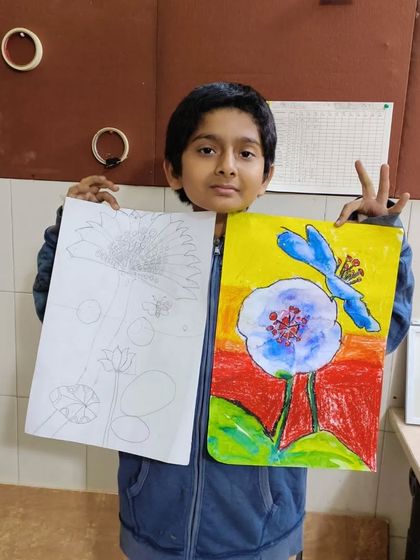 A young artist proudly displays his flower drawing and painting. This shows the process from the initial line drawing to the final colored piece.