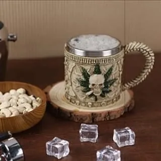 A thematic lifestyle shot of a unique, gothic-style beer mug featuring a skull and leaf motif. The scene is set with props like ice cubes and cashews to create a specific mood for niche barware products.