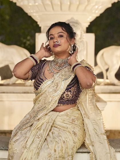 A beautiful shot of a bride with her hair in an intricate updo. The style is designed to showcase her stunning jewelry and the details of her saree.