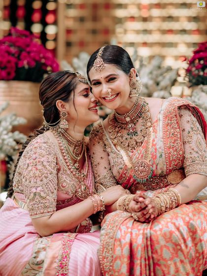 A close-up, heartwarming shot of two sisters. The intricate embroidery on both their blouses is clearly visible, showcasing our signature craftsmanship.