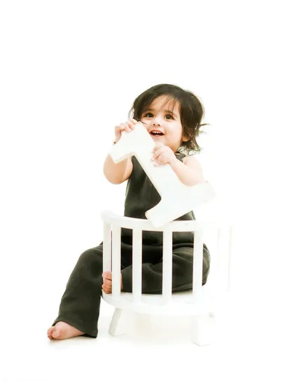 A solo shot of the birthday girl from the family session. She proudly holds her '1' prop, marking her special milestone.