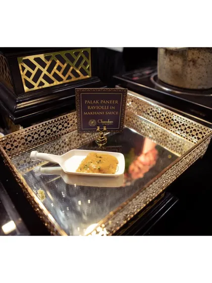A single serving of the Palak Paneer Ravioli in Makhani Sauce, elegantly plated on a mirrored tray. This dish perfectly represents my fusion food philosophy.