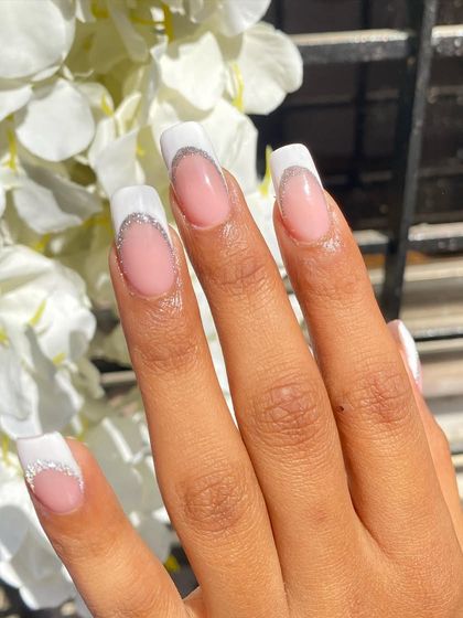 A close-up of the glitter French tip nails on a client. The sunlight really makes the silver glitter pop against the crisp white tip. This is a perfect look for weddings, parties, or just feeling fancy.