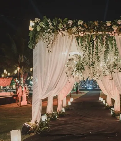This romantic evening entrance featured soft white drapes and hanging wisteria, lit by floor-level lanterns. It created a soft, dreamy, and intimate welcome for an unplugged wedding night.