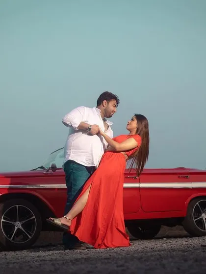 A romantic dance pose in front of a classic red Chevrolet convertible. This shot combines the appeal of a vintage prop with a beautiful outdoor location for a stylish pre-wedding picture.