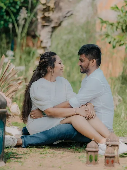 A sweet moment of the couple sitting together in a garden setting. The lanterns in the foreground add a charming, decorative element to the scene.