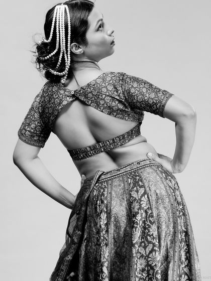 A black and white shot showcasing the back of a lehenga blouse and the model's pose.