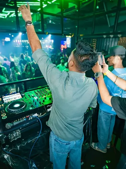 Celebrating a massive drop with the crowd. This is a classic DJ pose, connecting with the audience and sharing in the energy of the moment.