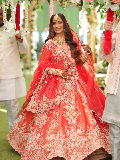 The bride's entrance under a floral canopy. Her radiant smile and flawless makeup make this a truly magical moment.
