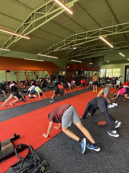 A moment of synchronized stretching during a large group bootcamp. We focus on every aspect of fitness, including mobility and recovery, to ensure everyone trains safely and effectively.