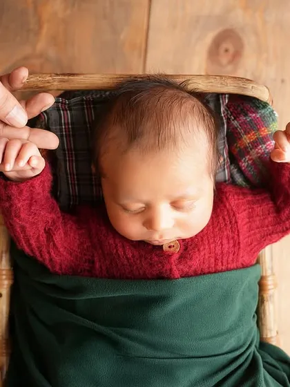 Sometimes, the biggest love stories are told in the tiniest details. A newborn's fingers wrapped around their parents' hands is a powerful symbol of connection, captured here in a rustic, warm setup for a Christmas-themed newborn session.
