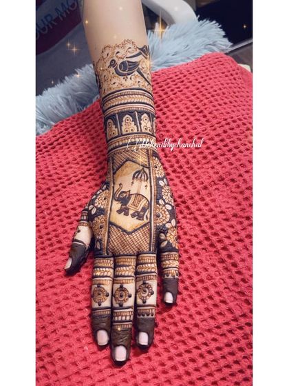 A close-up of a hand with a traditional design, featuring an elephant in a decorated frame on the palm and a bird motif on the arm.