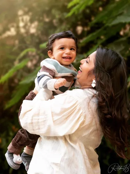 A mother celebrating her son's first birthday is also celebrating her own journey into motherhood. The joy in her eyes as she lifts him up is a beautiful testament to this special milestone.