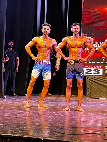 My men's physique athletes standing side-by-side on stage, both in incredible shape. This is the standard we aim for.