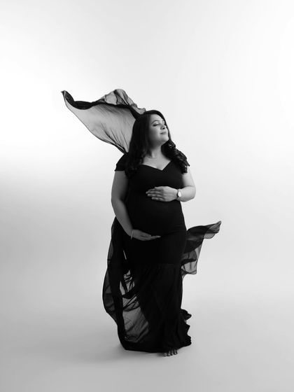 Another beautiful variation of the black and white fabric shot, capturing a different angle of the flowing material and the mother's graceful pose.