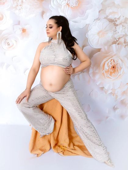 A confident and stylish pose in a sequined halter top and pants. This shot showcases a contemporary and fashionable approach to maternity photography.