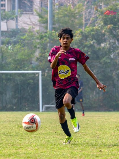 A young athlete sprints with the ball, showcasing the speed and agility we develop in our training.