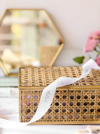 This shot focuses on the elegant, woven exterior of a gift box, with a branded ribbon draped artfully across it. The blurred background keeps the attention on the beautiful and sustainable packaging.