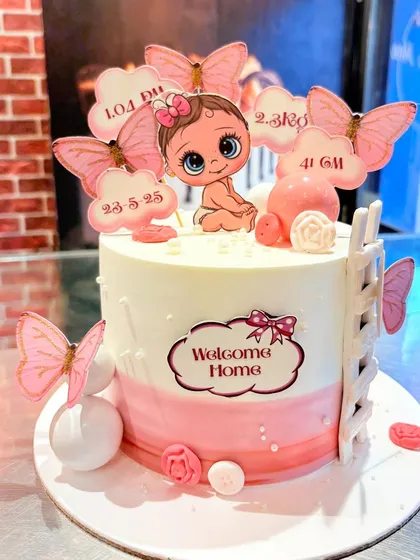 A "Welcome Home" cake for a newborn baby girl, decorated with pink butterflies and clouds showing her birth details.