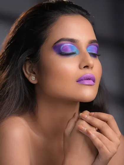 A vibrant, futuristic look with a stunning blend of purple and blue eyeshadow that extends up to the brows.