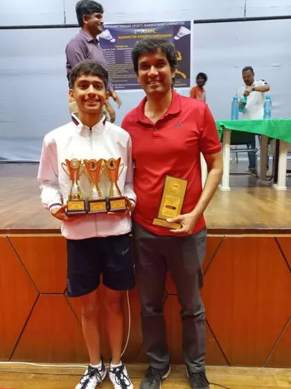 Anmol Sharma standing with his coach after a clean sweep at the Anushakti Nagar ASMC Badminton Championship. This triple victory is a result of consistent effort and rigorous training.