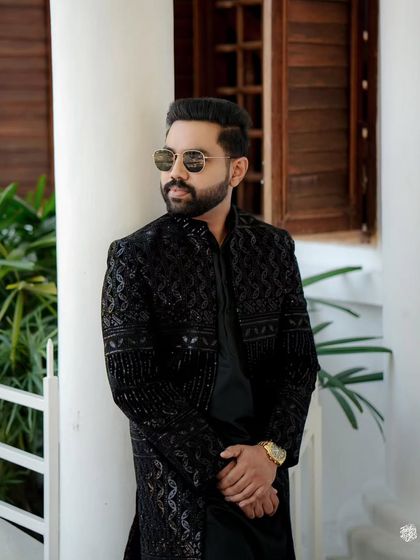 A solo shot of the groom from his engagement. The detailed black sherwani and confident pose make for a powerful image.