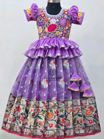 A stunning lavender lehenga with a floral and bird print border. The blouse is heavily embroidered with colorful flowers and has a tiered peplum.