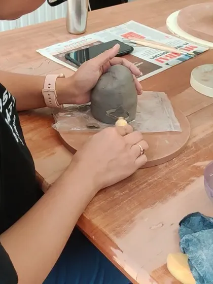 The careful process of refining a sculpture. Using simple wooden tools, a student adds the final touches to her piece.