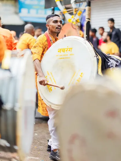 A dhol player with an energetic expression, fully engaged in the performance.