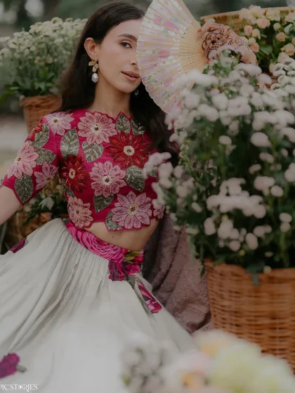 A dreamy, Pinterest-worthy shot from a Mehendi ceremony. The bride, surrounded by fields of flowers, looks like she's stepped out of a fairytale. The floral blouse and soft colors add to the romantic, bohemian vibe.