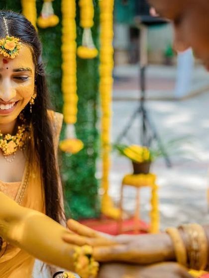 A quiet, beautiful moment during the Haldi rituals. A family member applies turmeric paste, and we capture the bride's serene and happy smile.