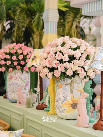 A close-up of the decor, featuring large floral-print vases filled with pink roses and whimsical animal figurines.