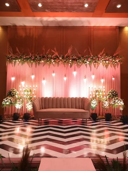 A beautifully decorated stage with a modern chevron-patterned floor and elegant floral arrangements.