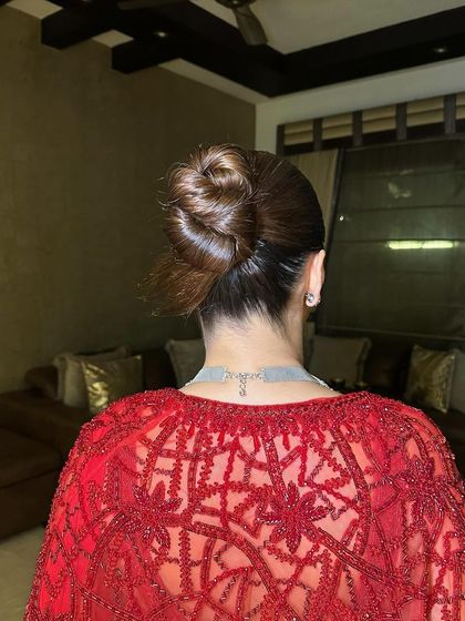 A detailed shot of the sleek, modern bun that complements the traditional red saree, showing how hairstyle completes the look.