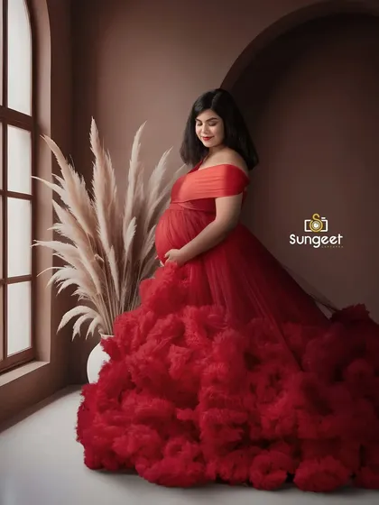 The rich red of this ruffled gown looks stunning against the warm, earthy brown backdrop. The window light adds a soft, natural feel.