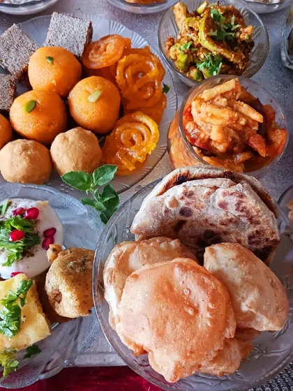 A focus on the breads and fried items from the Janmashtami feast. The spread includes pooris, puranpoli, khaman, and dahi pakodi made with a vegan curd, showcasing a complete and satisfying meal.