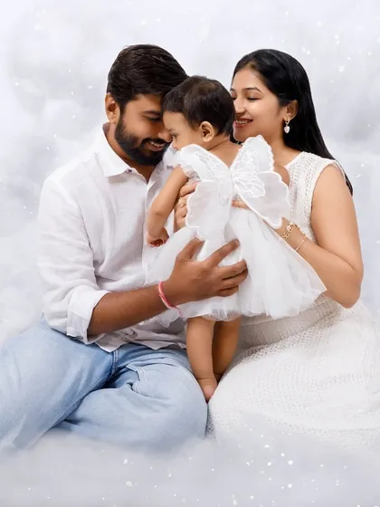A beautiful family portrait in the clouds. The parents embrace their little angel in this dreamy, all-white setup.